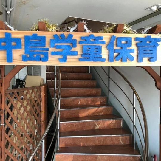「中島学童保育」と手書きされた看板と、2階へ上がる階段
