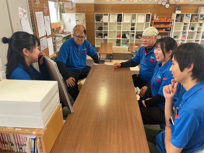 クラブの部屋で、長机を囲んで話し合っている職員たち