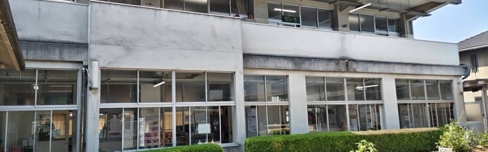 とみた児童クラブが入る校舎の外観。窓の下に植え込みと花壇が続く